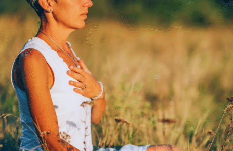 Mujer con los ojos cerrados, rodeada de sombras suaves y luz dorada, simbolizando la transformación del dolor en sabiduría ancestral.