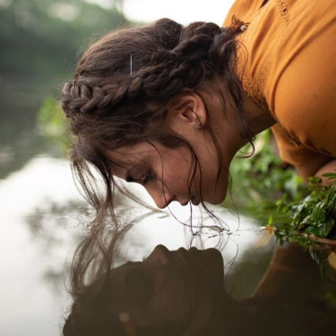 Mujer viendo su reflejo en el agua, meditando y conectando con su esencia interior. Autoestima y sanación.